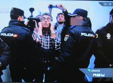 Человек в клетчатой рубашке окружён полицейскими и журналистами