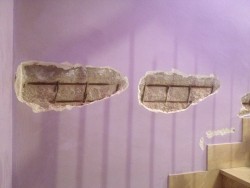Отслоившаяся штукатурка на стене с видимыми кирпичами