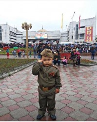 Маленький мальчик в военной форме с салютом
