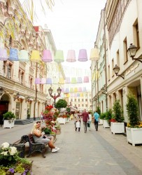 Уютная улица с цветами и фонарями, люди гуляют